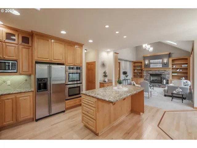 a large kitchen with stainless steel appliances kitchen island granite countertop a large kitchen island and a refrigerator