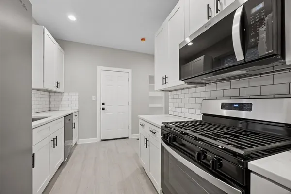 a kitchen with stainless steel appliances a stove microwave and sink