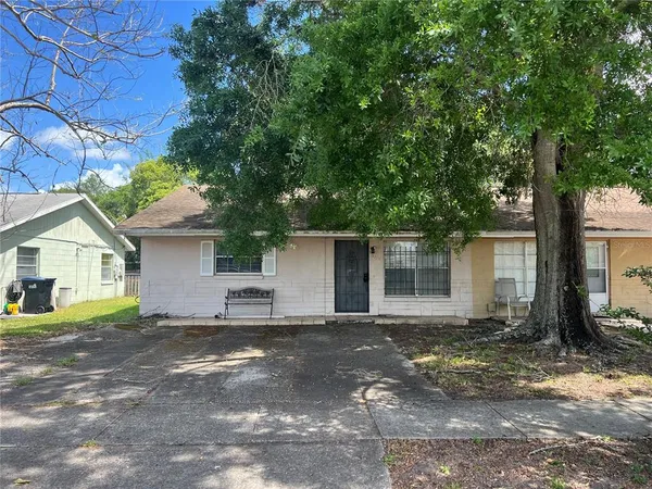a view of a house with a yard and large tree
