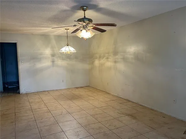 an empty room with a glass door and chandelier fan