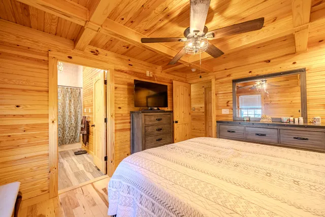 a spacious bedroom with a large bed a chandelier and flat screen tv