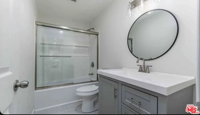 a bathroom with a sink a mirror a toilet and shower