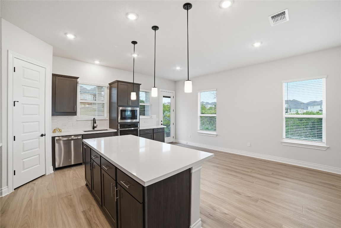 716 Coppell Court Leander, TX 78641 - Photo 12 of 40 a large kitchen with stainless steel appliances a large counter top a sink a stove and a wooden floors
