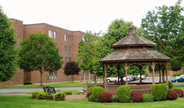 a front view of a building with trees and umbrellas