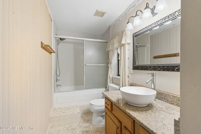 a bathroom with a granite countertop sink toilet a mirror and shower