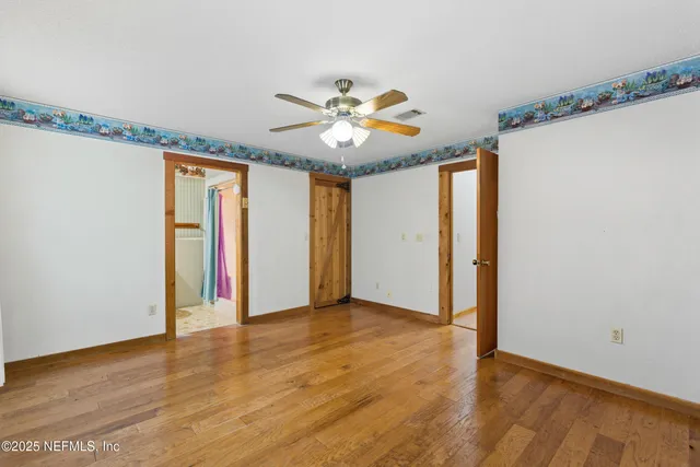 a view of an empty room with window and a ceiling fan