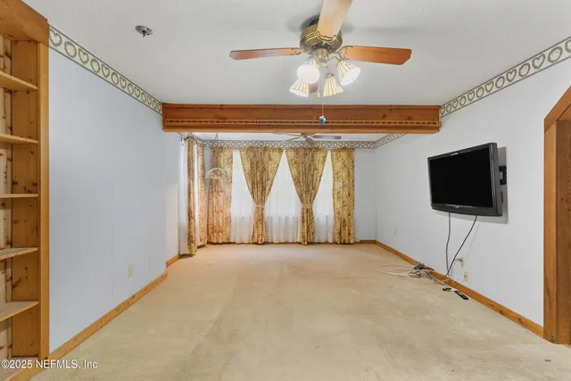 a view of a livingroom with a flat screen tv a ceiling fan and window