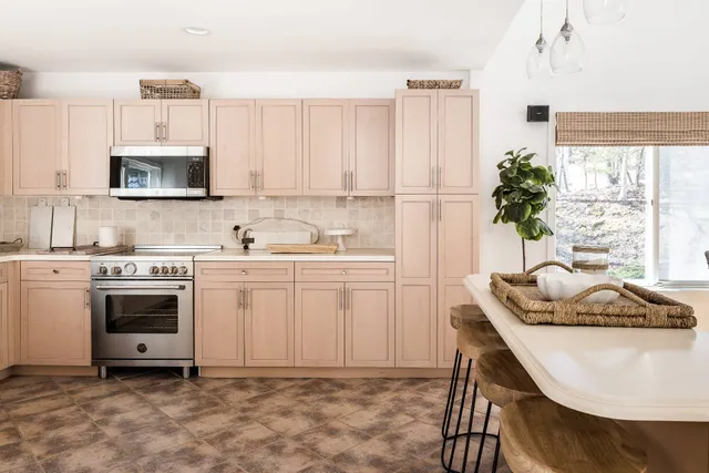 a kitchen with stainless steel appliances granite countertop a stove a sink a microwave a refrigerator and white cabinets