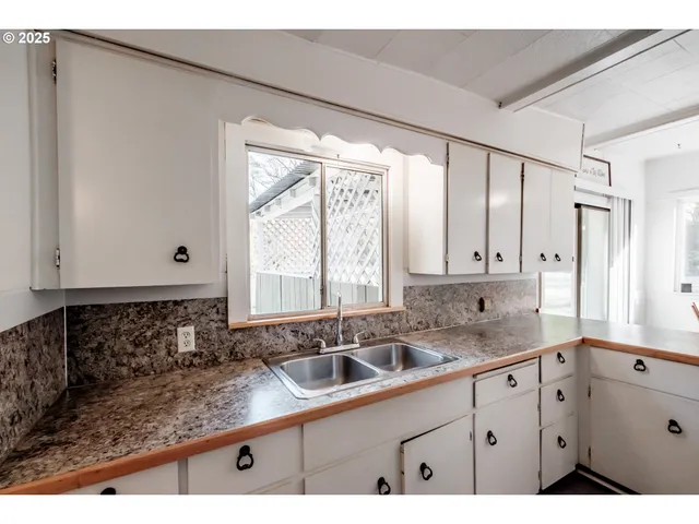a kitchen with granite countertop white cabinets and sink
