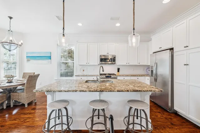 a kitchen with stainless steel appliances granite countertop a stove top oven a sink dishwasher and cabinets with wooden floor