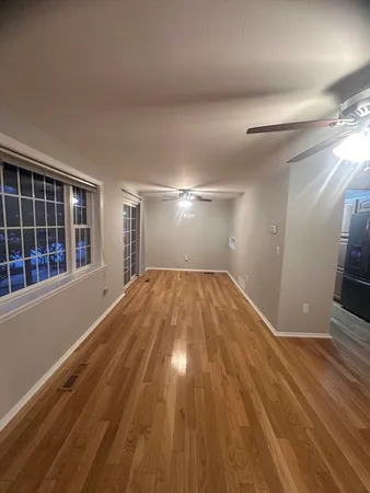 a view of empty room with wooden floor and fan