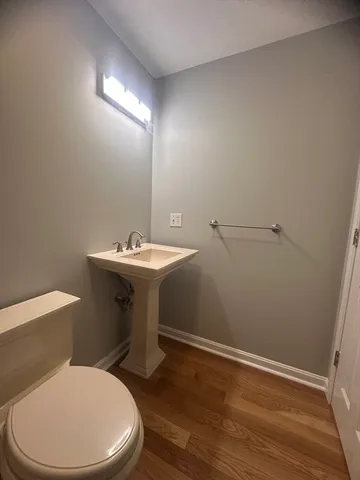 a bathroom with a toilet a sink and wooden floor