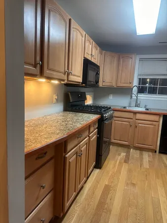 a kitchen with stainless steel appliances granite countertop wooden cabinets granite counter tops and a hard wood floors