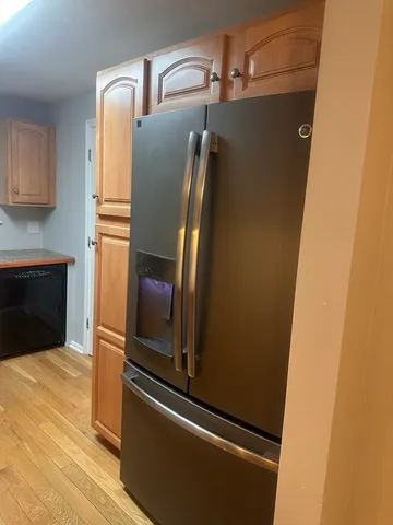 a close view of a refrigerator in kitchen and a wooden floor