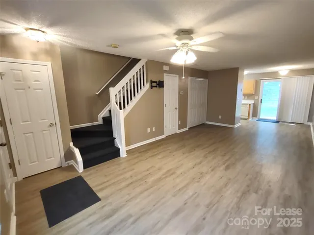 a view of an empty room with wooden floor and staircase