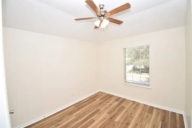 an empty room with a window and a fan