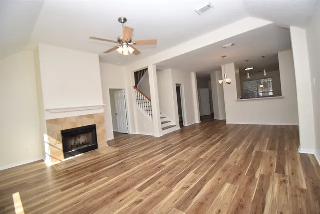 a view of an empty room with wooden floor fireplace and a window