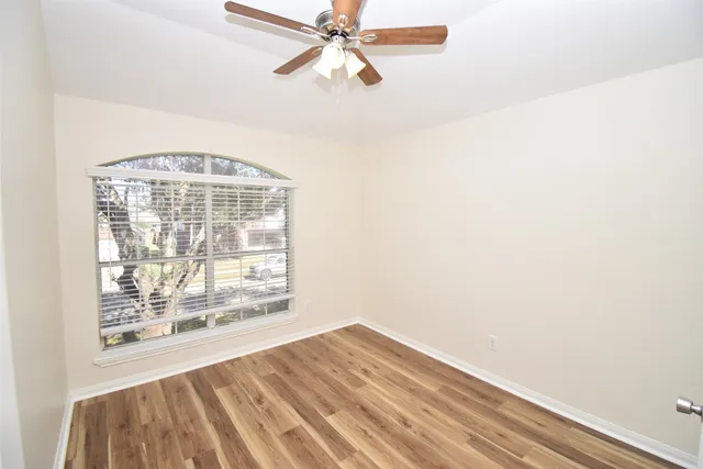 a view of an empty room with wooden floor and a window