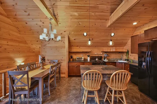 a kitchen with stainless steel appliances granite countertop a stove a refrigerator a dining table and chairs with wooden floor