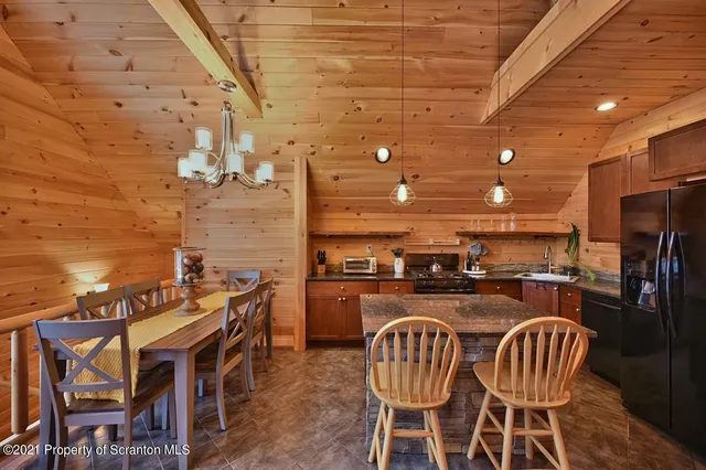 a kitchen with stainless steel appliances granite countertop a stove a refrigerator a dining table and chairs with wooden floor