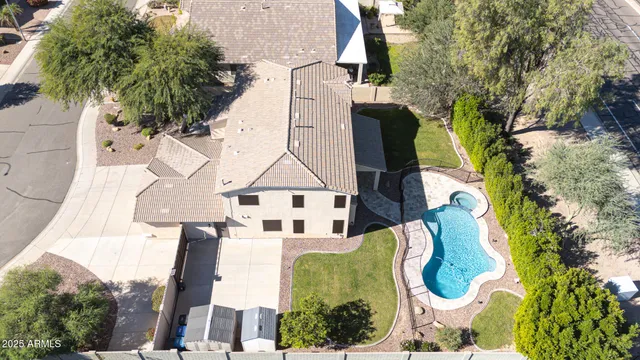 an aerial view of a house with swimming pool and large trees
