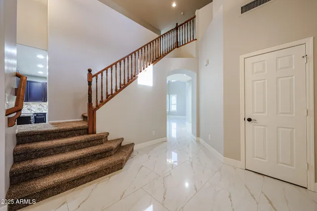 an empty room with wooden floor chandelier fan and windows
