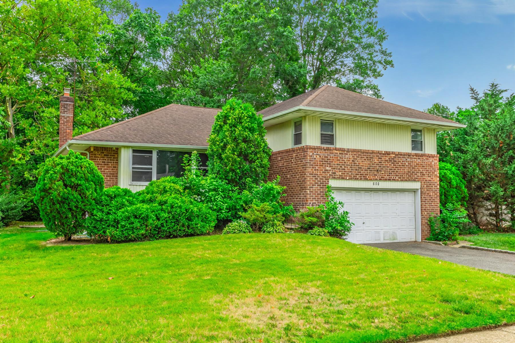 View of front of property featuring driveway, brick siding, a chimney, an attached garage, and a front yard