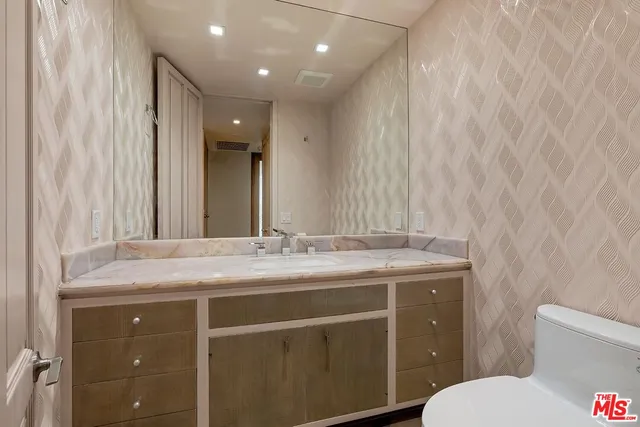 a bathroom with a granite countertop sink toilet and mirror