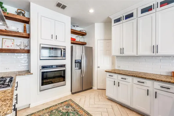 a kitchen with stainless steel appliances granite countertop a refrigerator and a stove top oven