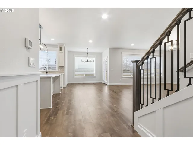 a view of a kitchen and an empty room with wooden floor