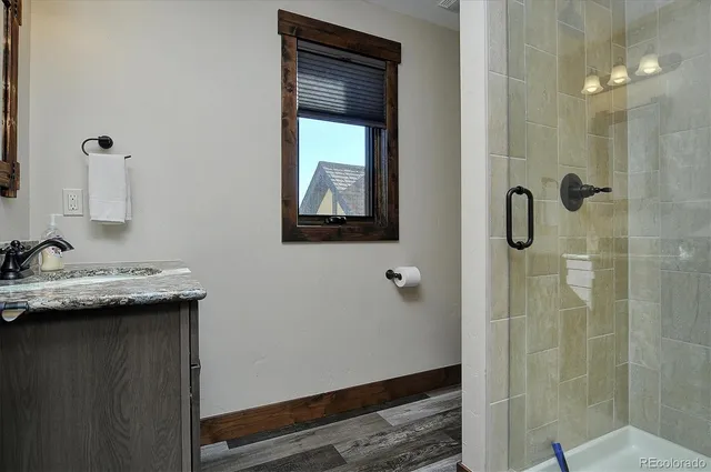 a bathroom with a granite countertop sink a mirror and shower