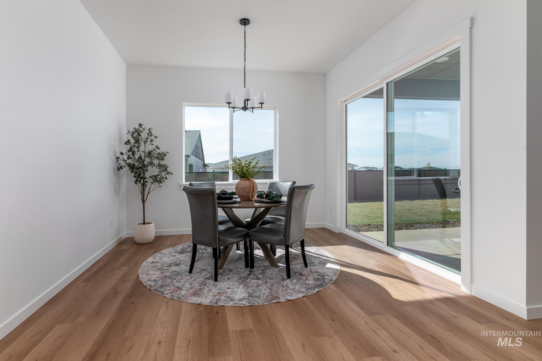 5402 Juliet Rose Avenue Caldwell, ID 83607 - Photo 6 of 20 Dining area featuring wood-finish flooring, a contemporary chandelier, and a large window overlooking the exterior