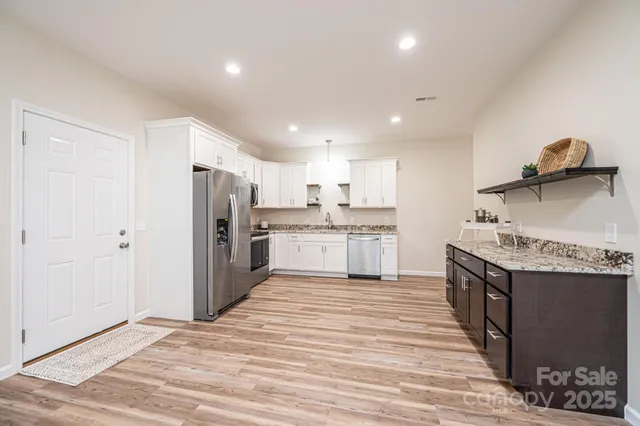 a kitchen with stainless steel appliances granite countertop a stove top oven a sink and a refrigerator