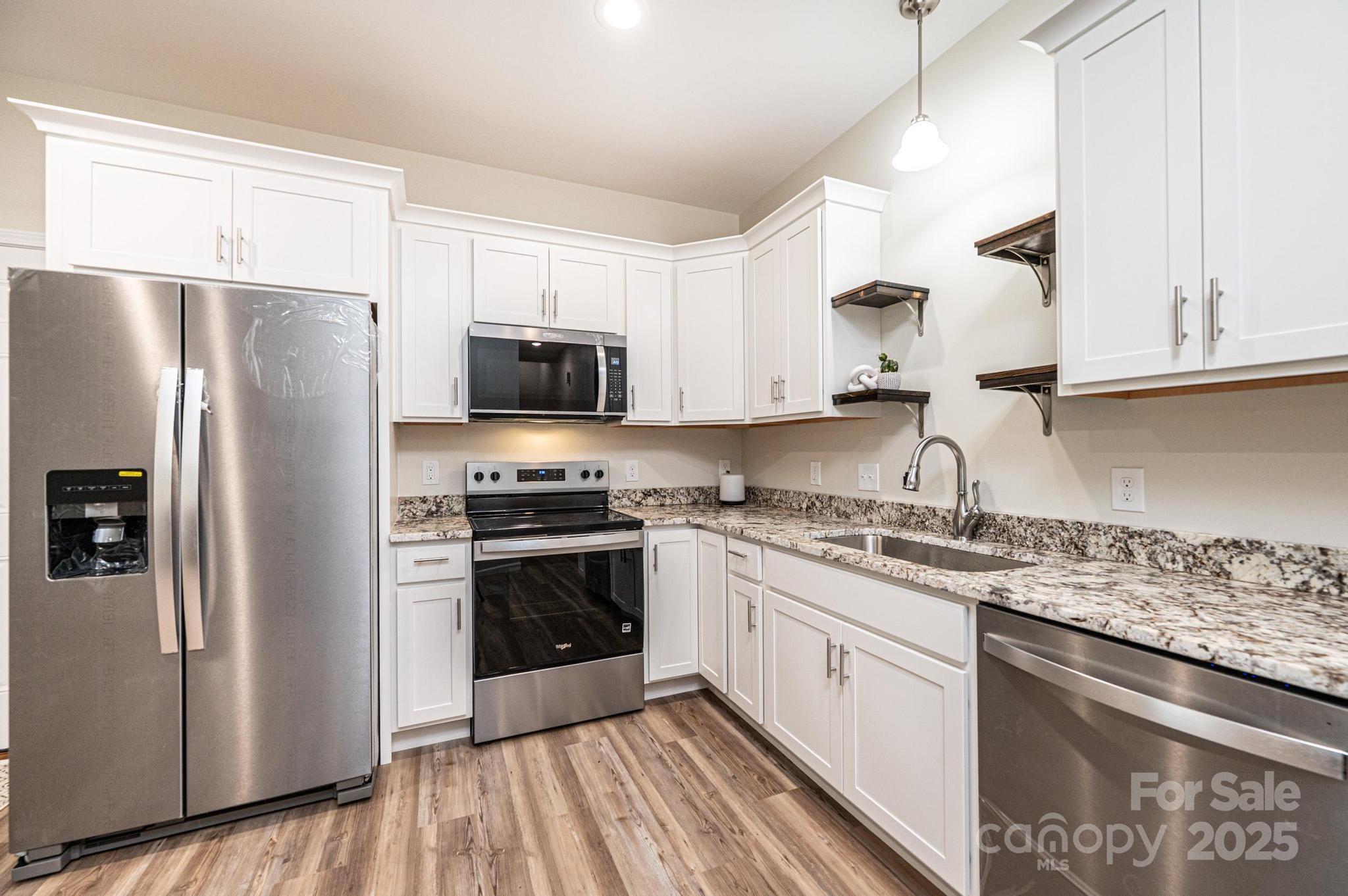 1214 Winter Place Lenoir, NC 28645 - Photo 6 of 19 a kitchen with stainless steel appliances granite countertop a stove a sink dishwasher a refrigerator and white cabinets with wooden floor