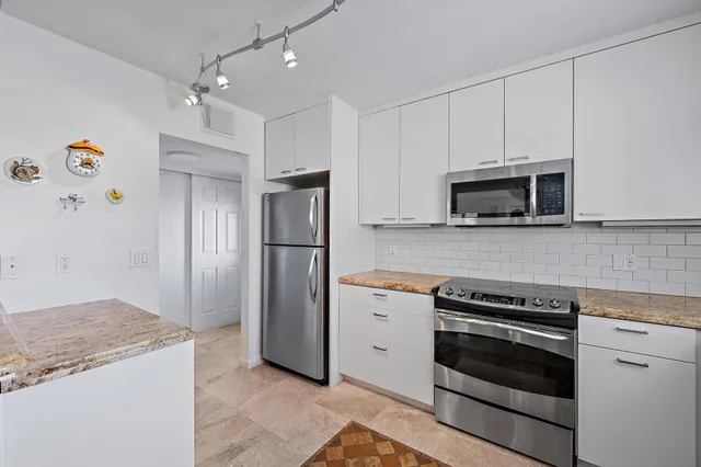 a kitchen with granite countertop a refrigerator and a stove top oven