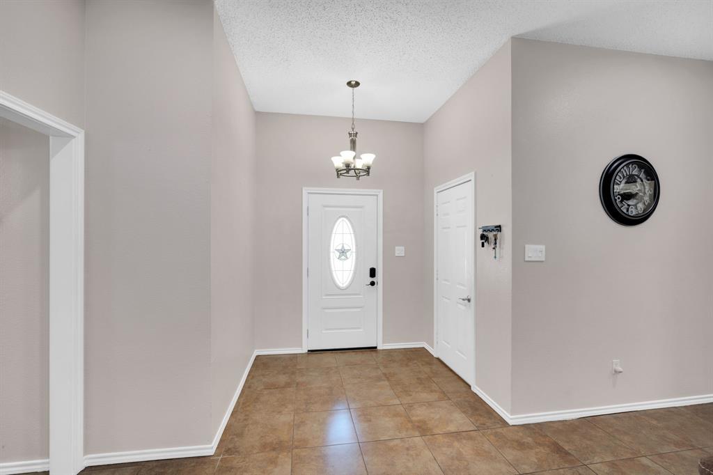 1001 Short Line Boulevard Midlothian, TX 76065 - Photo 12 of 26 Entry foyer featuring a white oval-lite front door, ceramic tile flooring, a vaulted ceiling, and an overhead chandelier