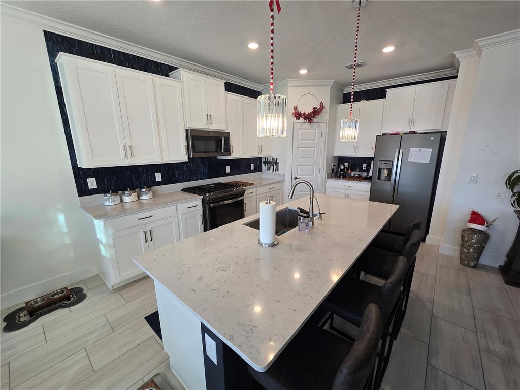 8280 Rolling Tides Drive New Port Richey, FL 34655 - Photo 12 of 49 a kitchen with stainless steel appliances granite countertop a refrigerator a stove a sink a dining table and chairs with wooden floor