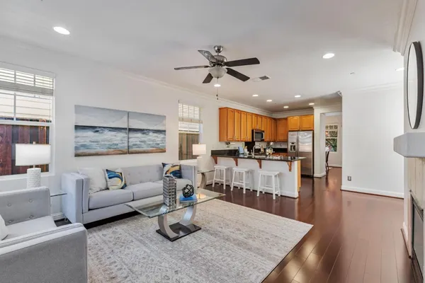 a living room with furniture kitchen view and a wooden floor