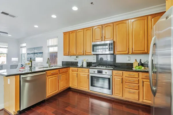 a kitchen with stainless steel appliances granite countertop wooden cabinets a sink and dishwasher with wooden floor