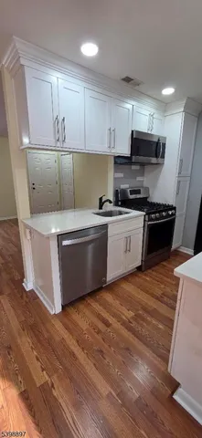 a kitchen with stainless steel appliances wooden floors and view living room