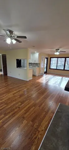 a view of an empty room with kitchen and a window