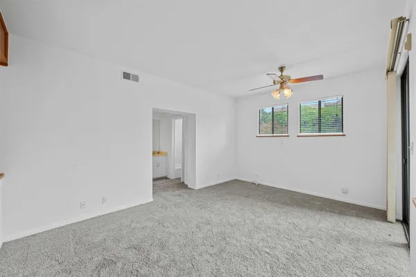 an empty room with windows and fan