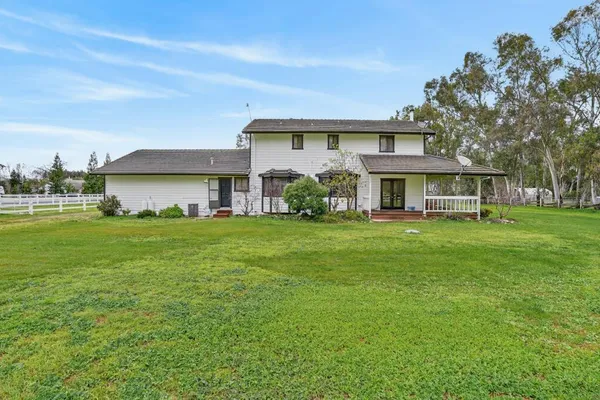 a view of a house with a big yard and large trees