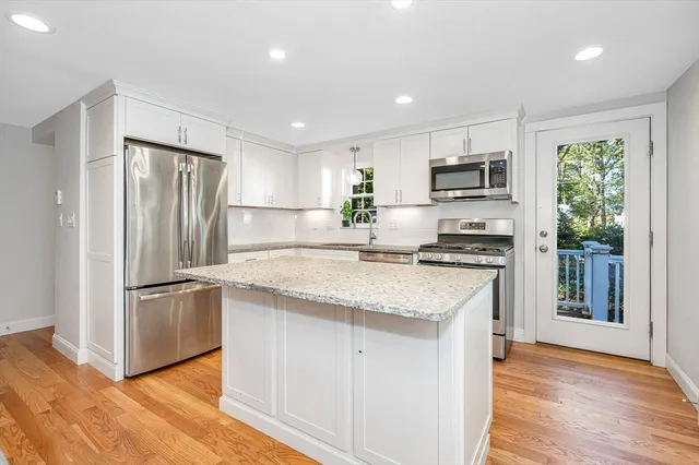 a kitchen with kitchen island granite countertop a refrigerator stove top oven and sink