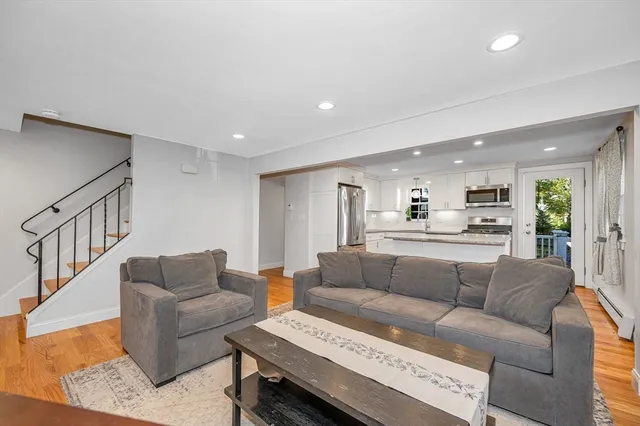 a living room with furniture kitchen view and a wooden floor
