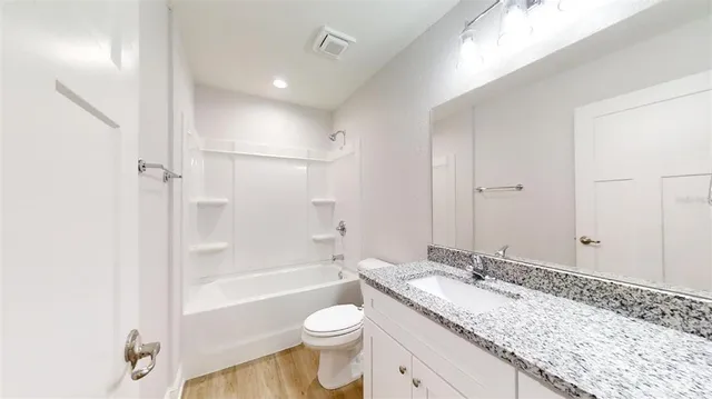 a bathroom with a granite countertop sink a mirror and a toilet