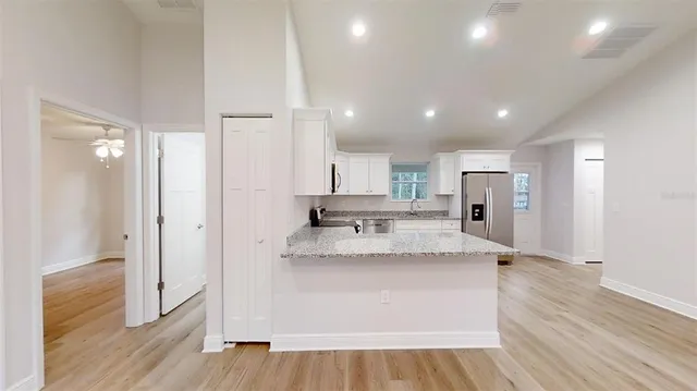 a kitchen with stainless steel appliances white cabinets and wooden floor
