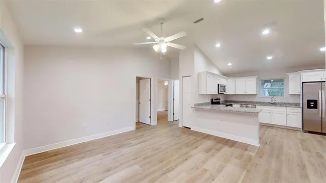 a view of a hallway with wooden floor and a kitchen