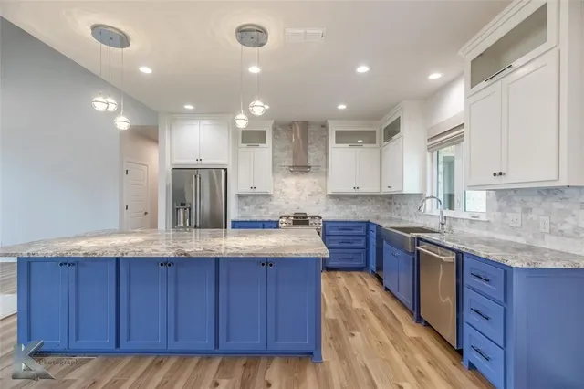 a kitchen with stainless steel appliances granite countertop wooden floors wooden cabinets and window
