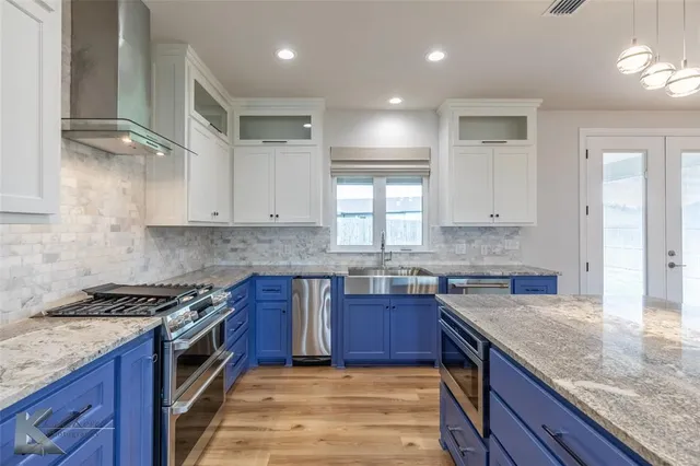 a large kitchen with granite countertop a large counter top stainless steel appliances and cabinets